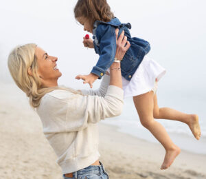 JoAnna holding daughter in air on beach